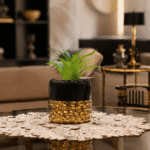 أصيص سيراميك أسود لامع بقاعدة ذهبية منقوشة مع نبات صناعي